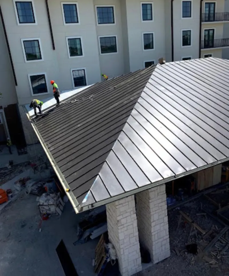 Crew installing standing seam metal roof panels on a commercial project in Collinsville